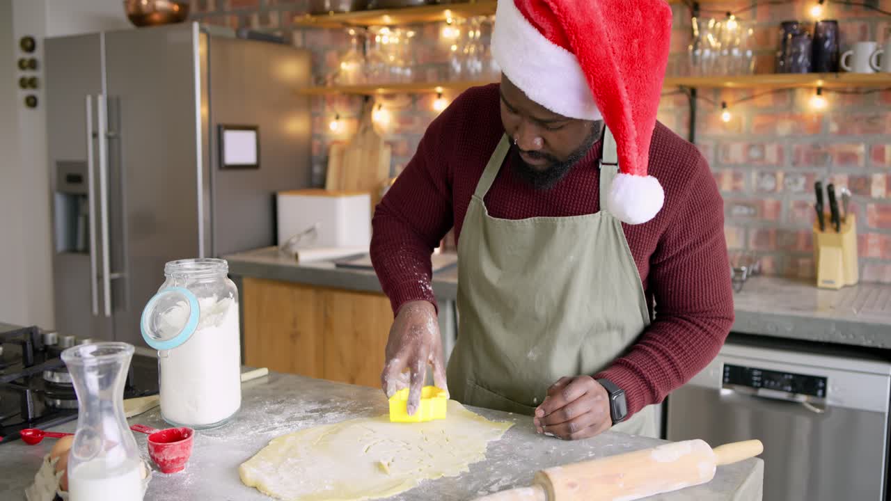 Dusting dough with flour, man is stamping leaf and circle shapes on kitchen countertop for cookies