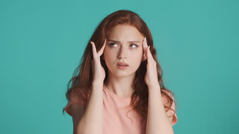 redheaded girl in front of camera on turquoise background.