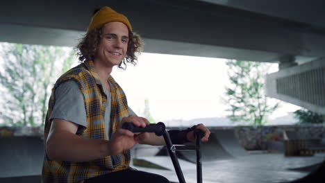 Happy-hipster-gesturing-hand-at-skatepark.-Handsome-man-smiling-on-camera.