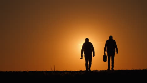 two farmers walking at sunset