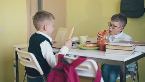 Schulkind-Isst-Pizza-Und-Freund-Liest-Am-Tisch-Lehrbuch