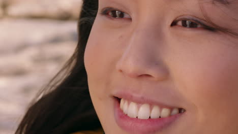 close up portrait of happy asian woman smiling enjoying sunny day relaxing on summer vacation with wind blowing hair