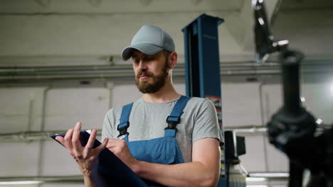 man with cap writing at the garage