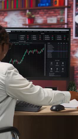 vertical video forex trader browsing though stock exchange portfolio pages at computer desk