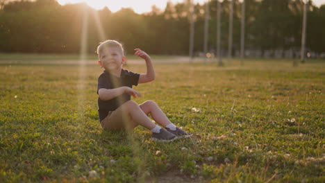 Smiling-boy-waves-off-insects-swarm-on-lawn-at-sunset