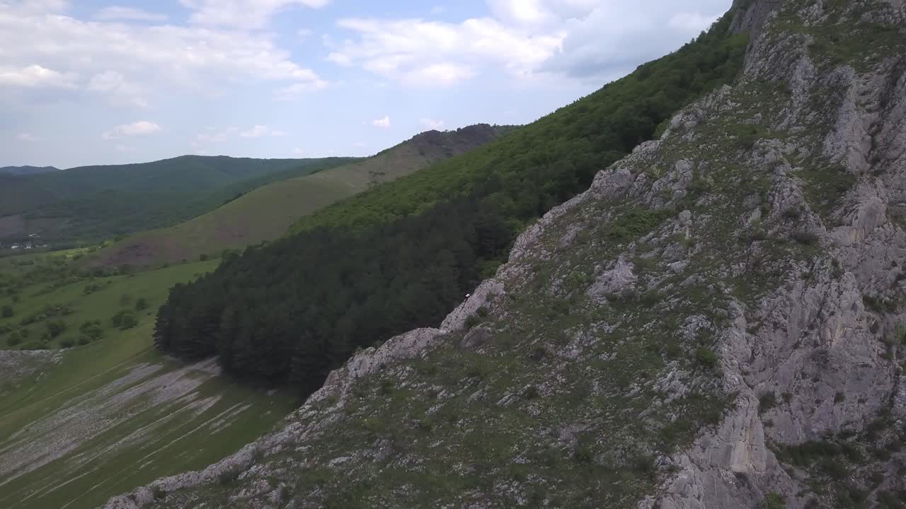 Aerial View Of Hiker Climbing Up a Rock Mountain In Nature With Green Vegetation