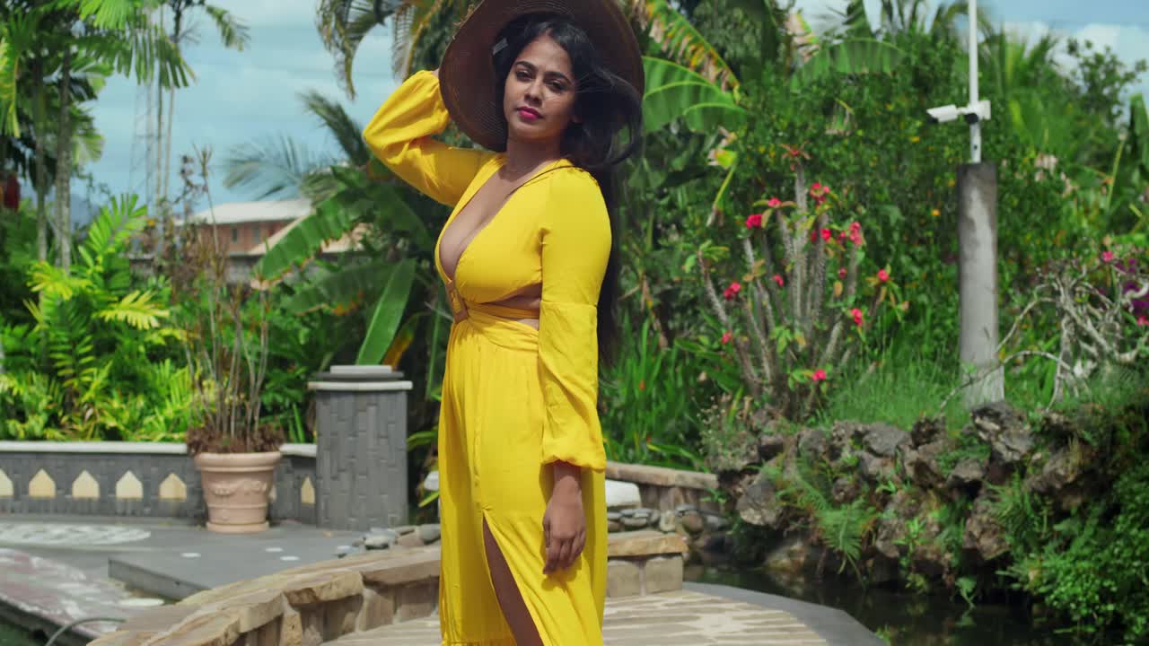 mujer con vestido amarillo en un jardín tropical