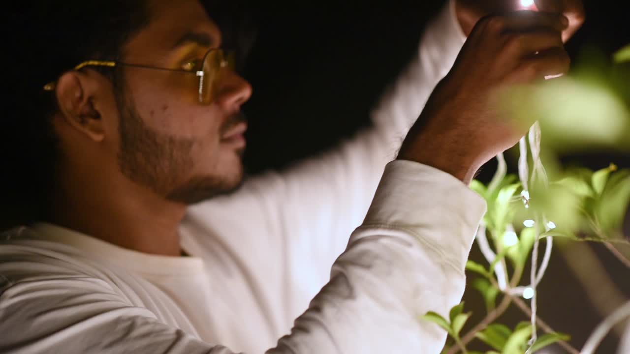 세련된 10대 남성은 파티, 슬로우 모션을 위해 led 조명 와이어로 식물을 장식합니다.