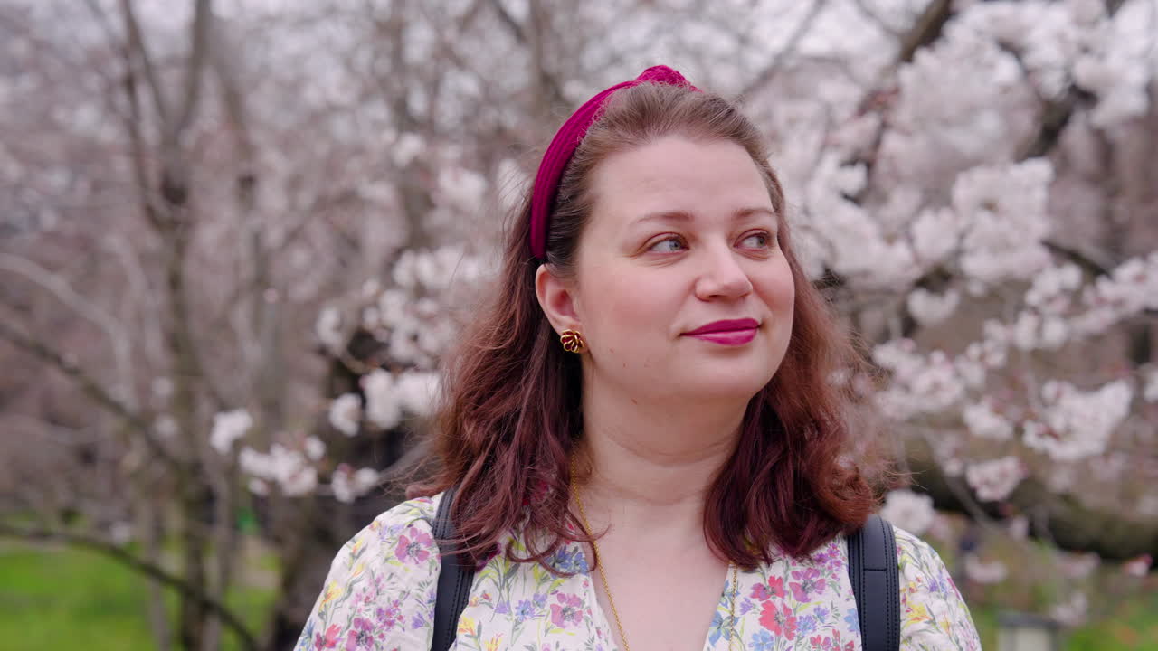 행복 한 여자 는 일본 의 교토 식물원 에서 사쿠라 나무 의 아름다움 을 감상 하고 있다