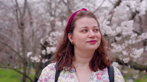 happy woman admiring the beauty of sakura trees at kyoto botanical garden in japan