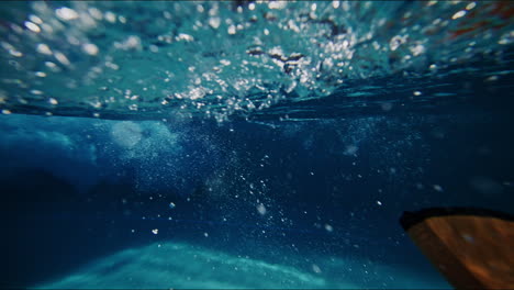 underwater slow motion backlit view of waves forming in wavepool, with light reflecting off pool bottom creating wavy patterns
