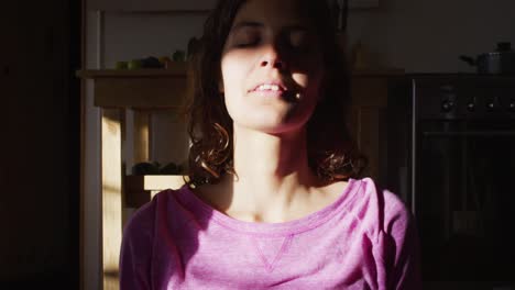 relaxed mixed race woman practicing yoga, sitting meditating and smiling in cottage bedroom