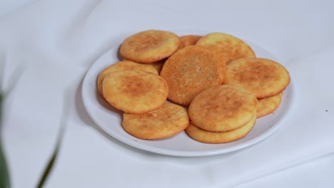 a hand gently picks a golden butter cookie from a white plate. perfect close-up shot for dessert, bakery, or traditional food content in ultra-clear 4k. clean, minimal white background.