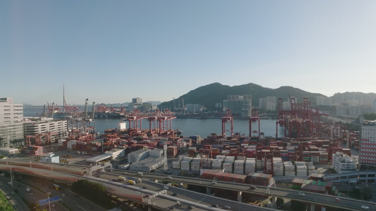 Aerial rising establishing shot over Hong Kong industrial port facing Tsing Yi on clear sunny day