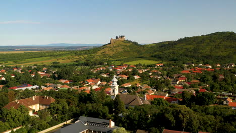 wide rotating drone shot of the boldogkő castle in hungary and the town below