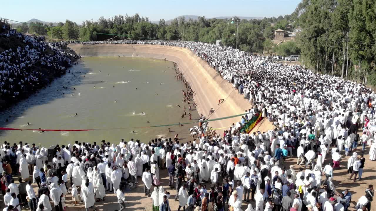 Aerial footage over Ethiopian Timkat baptism Ceremony in water Resrvoir