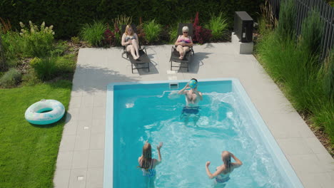 Familia-Amigable-Relajándose-Junto-A-La-Piscina,-Pasando-Un-Buen-Rato-Juntos