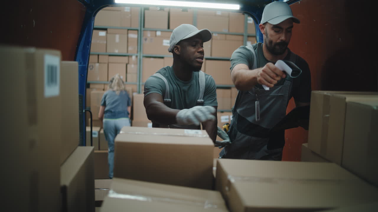 Logistics workers scanning and handling packages in a delivery truck or warehouse