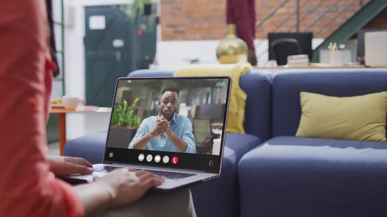 mujer biracial usando computadora portátil para videollamada, con un colega de negocios en la pantalla