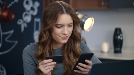 beautiful businesswoman typing card number on smartphone at home office.