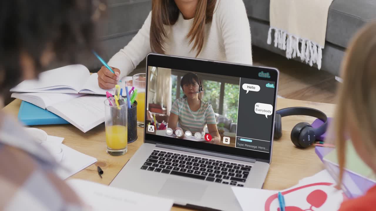 Estudiantes diversos tomando clase durante una videollamada por portátil con chat a cámara lenta.