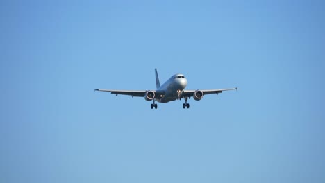 jet airplane landing with blue sky background, front view approach