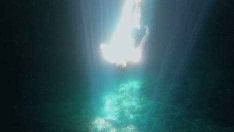 a diver is thoroughly enjoying his underwater adventure, completely immersed in the mesmerizing spectacle of sunlight casting stunning illusions through the pure, crystalline water