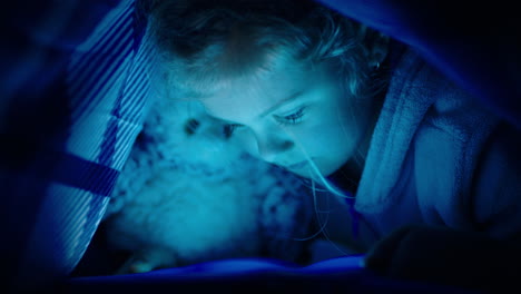 happy-little-girl-using-digital-tablet-computer-under-blanket-enjoying-learning-on-touchscreen-technology-playing-games-having-fun-at-bedtime