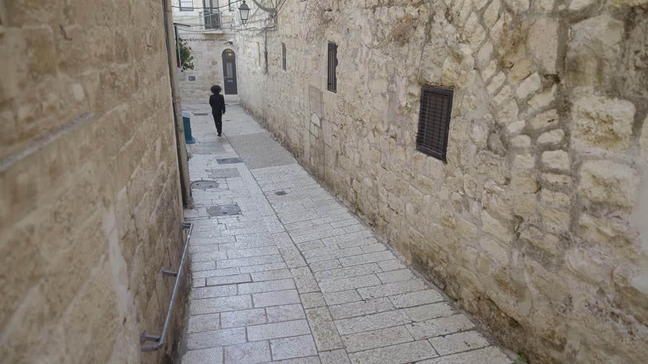 High angle shot of Orthodox Jew walking through a long narrow street at the Old City of Jerusalem, Israel