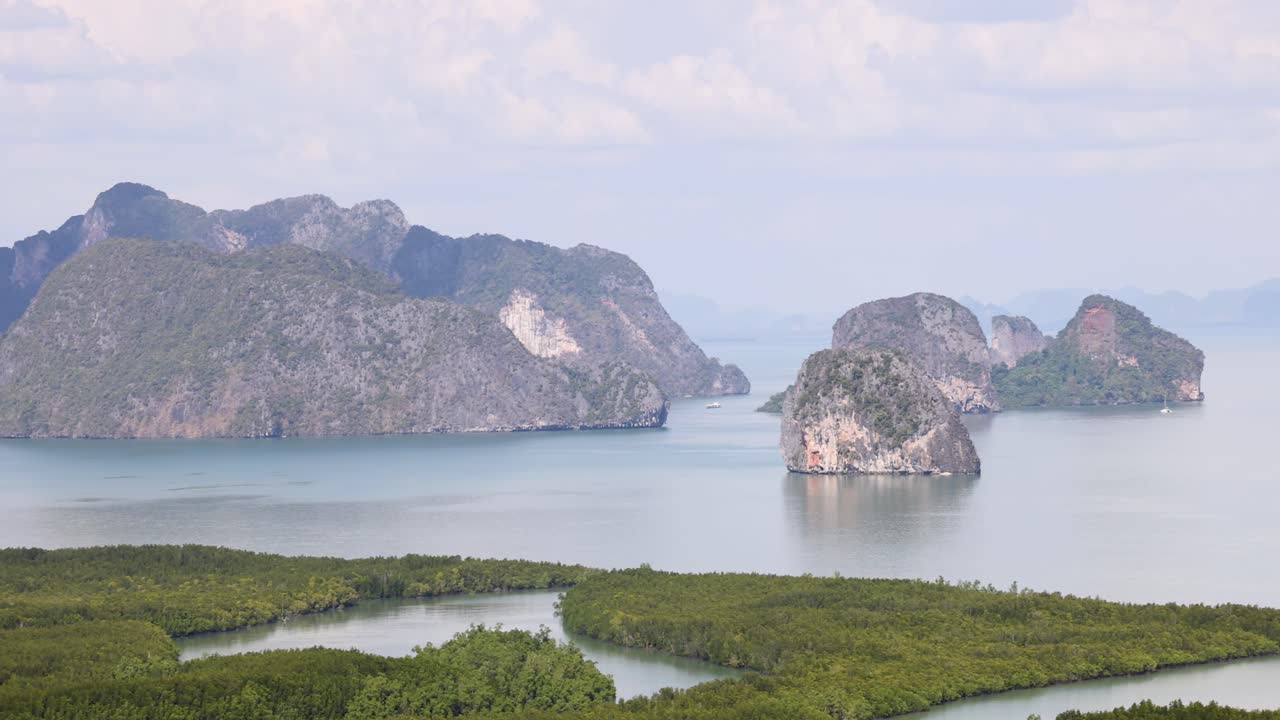 Panoramic view of Phang Nga Bay's limestone cliffs and lush greenery under bright daylight, showcasing natural beauty and tranquility
