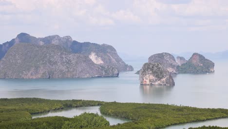 panoramic view of phang nga bay's limestone cliffs and lush greenery under bright daylight, showcasing natural beauty and tranquility