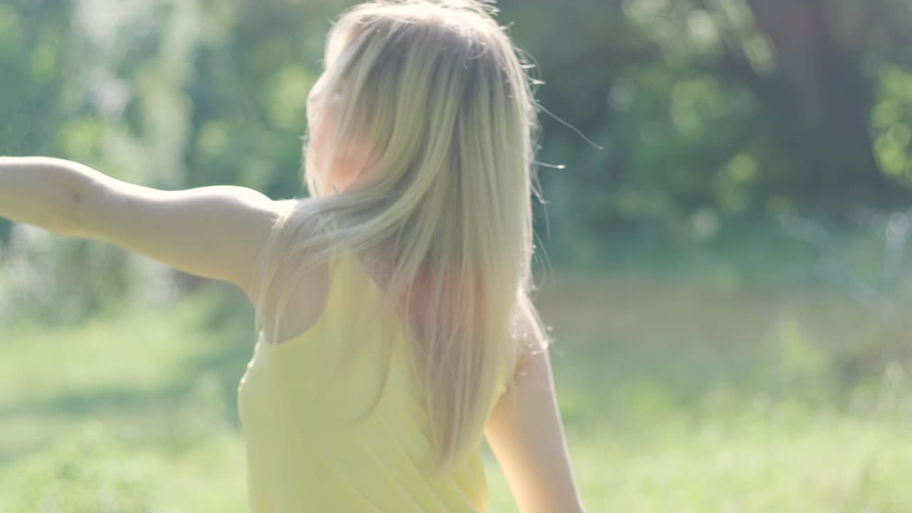 아름다운 젊은 소녀가 자유의 춤을 추고 있습니다. 여름 공원에서 뒷면에 나무가 있습니다.