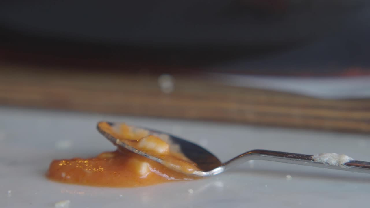 Spoon with spilled food on a white surface