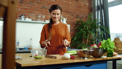 Woman-slicing-tomato-on-cutting-board.-Girl-throwing-vegetables-in-salad-bowl.