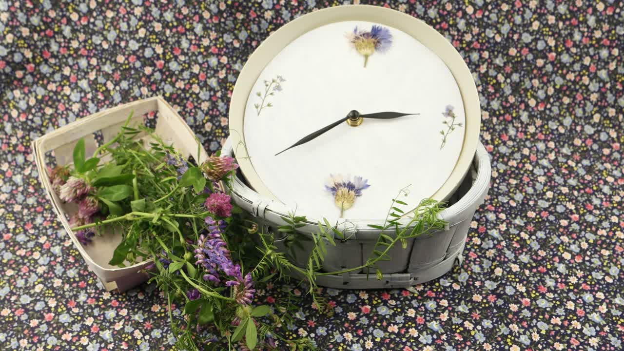 A clock and flowers are on the  fabric with a floral pattern, floristic composition