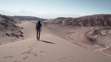 man walking on desert sand dunes