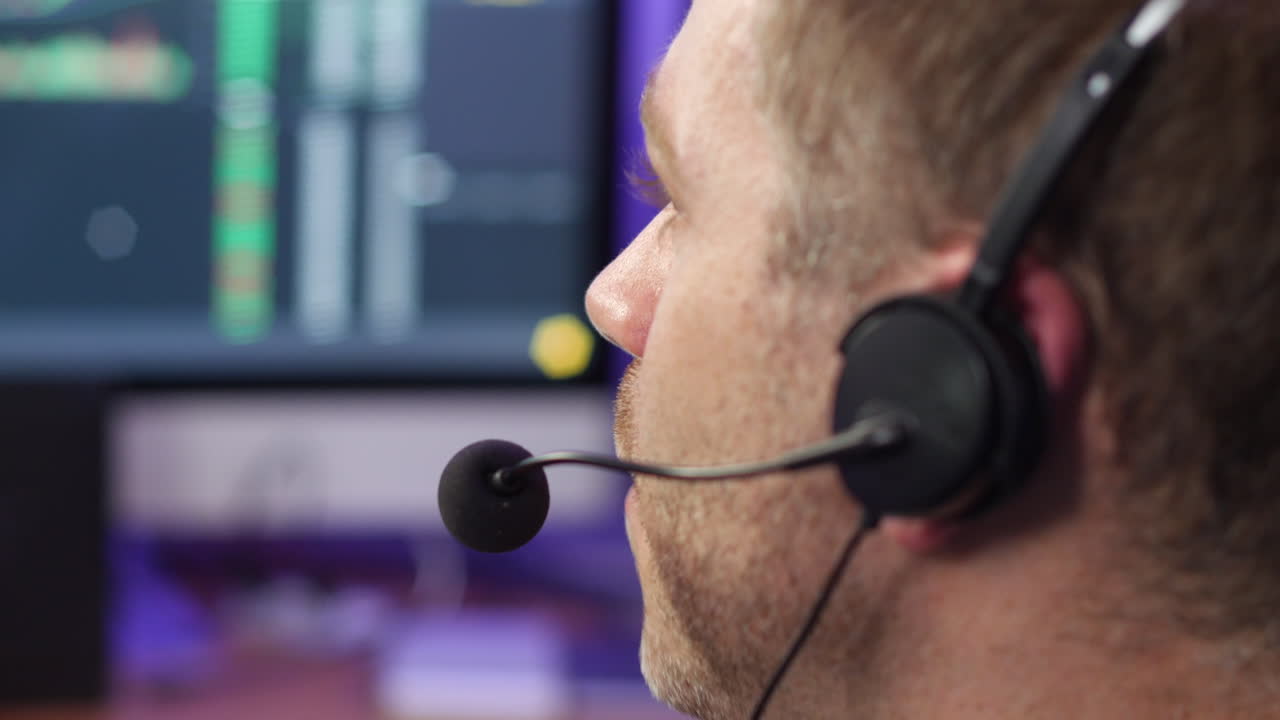 Unrecognizable man in technical support talking on phone headset at trading broker desk