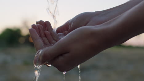 close up woman hands holding water drinking freshwater on rural farm at sunrise