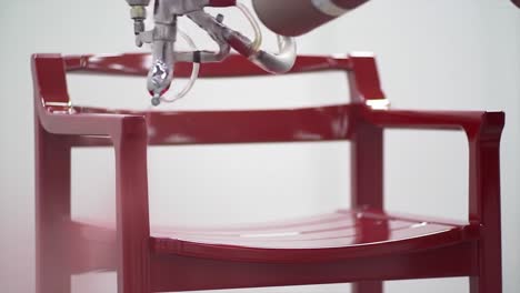 a vibrant red chair being sprayed with paint, showcasing the process of adding color to a simple design for modern home decor