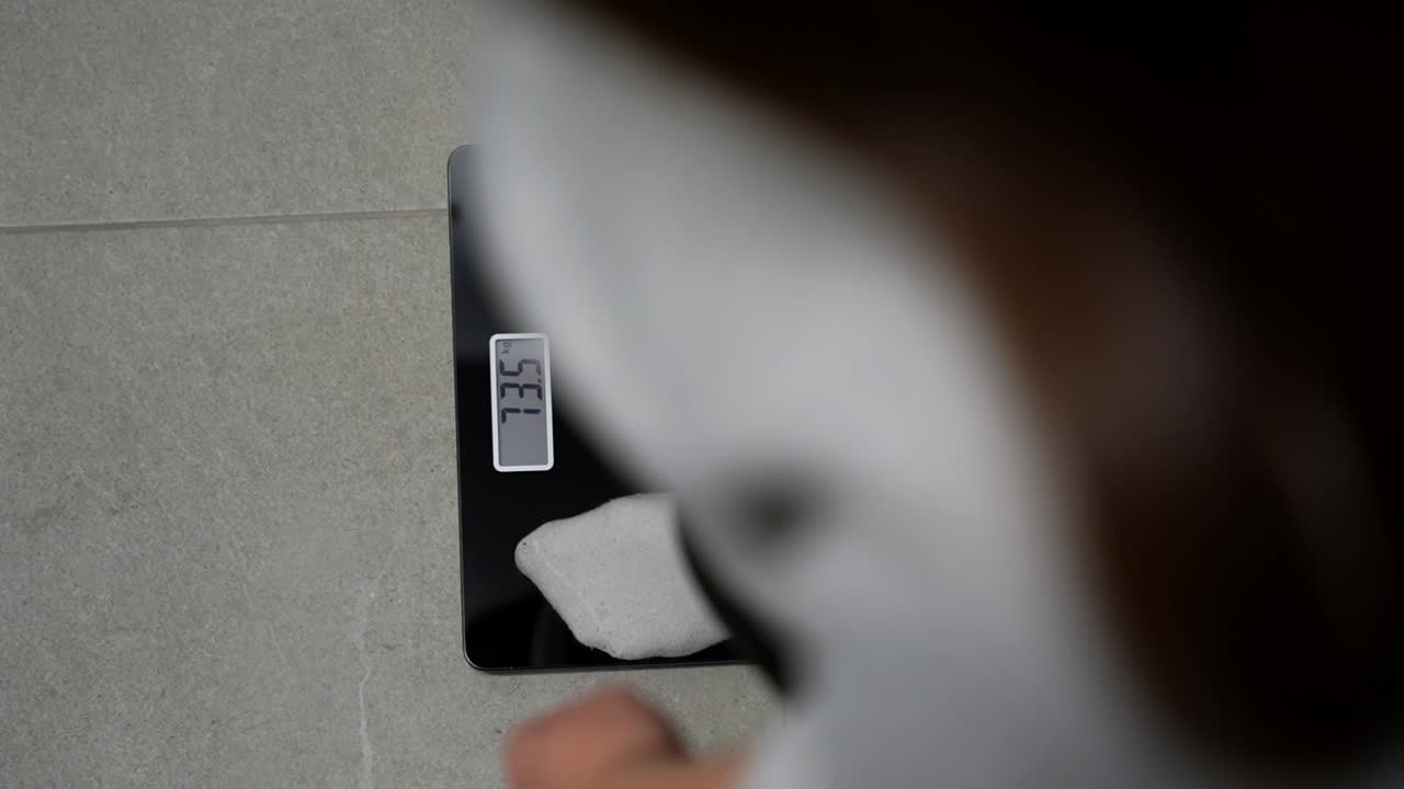 Pregnant woman stepping on a scale to check her weight
