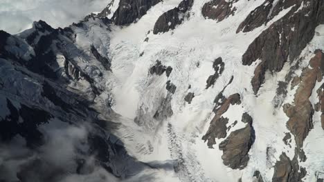 hooker glacier, southern alps, new zealand with clouds, snow and rocky mountains from scenic airplane flight