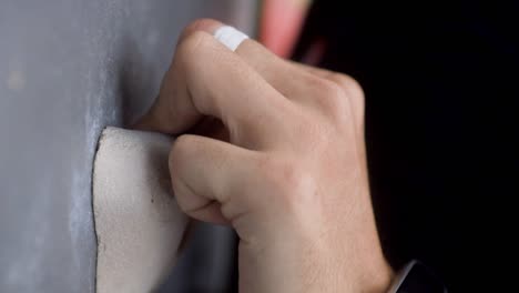 caucasian hand gripping a hold using a few fingers, rock climbing