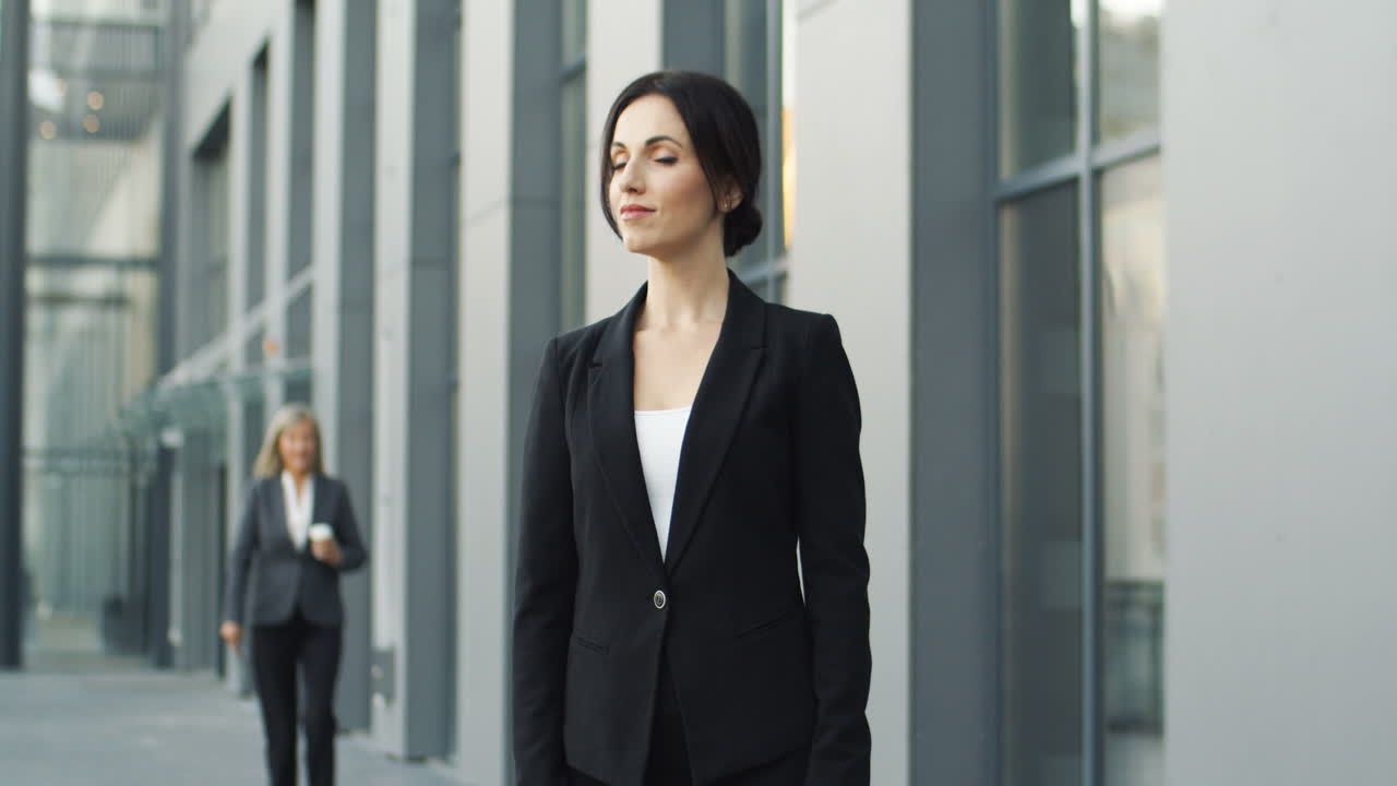 mujer de negocios sonriente en la calle y mirando a la cámara con los brazos cruzados