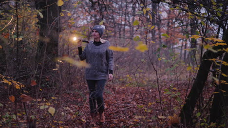 una mujer con una linterna camina por un bosque oscuro buscando algo buscando a la señorita