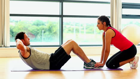 un hombre guapo haciendo abdominales en el gimnasio.