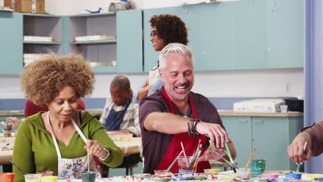 Group-Of-Mature-Students-Attending-Art-Class-In-Community-Centre-Being-Helped-By-Teacher