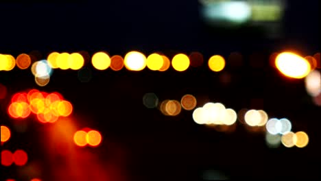 los círculos de bokeh en movimiento de las luces de los coches que corren por las calles de la ciudad. el fondo borroso de la ciudad, el tráfico nocturno.