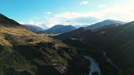 Aerial-view-over-kawarau-river-surrounded-by-mountains-during-sunny-day---connecting-queenstown-and-cromwell-in-New-Zealand