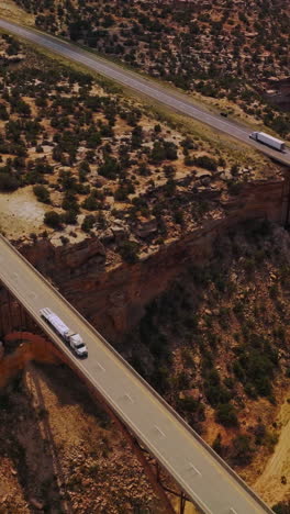 bridges joining the sides of huge ditch in the land of a desert. drone footage over the landscape covered with little bushes. vertical video
