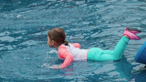 Hübsches-Kleines-Mädchen,-Das-Im-Wasserpfützenbecken-Auf-Dem-Bauch-Liegt-Und-Mit-Den-Händen-Planscht